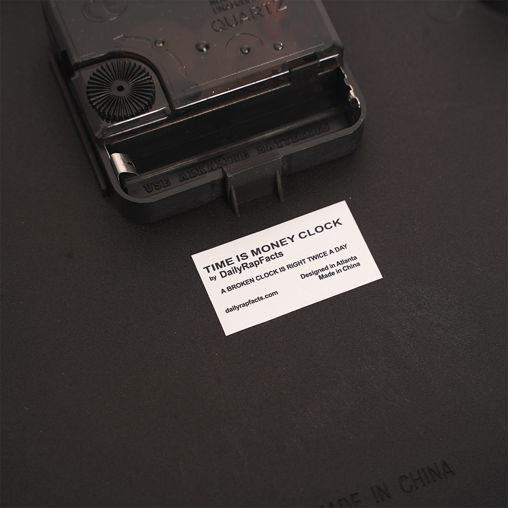 back of Black Time is Money clock mechanism on a dark surface with a white label.